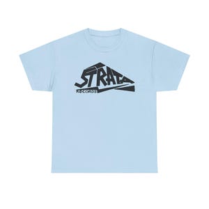 May include: Light blue t-shirt with a black graphic of the word "STRATA" in a stylized font, with "RECORDS" below. The shirt is a solid color and has a crew neck.
