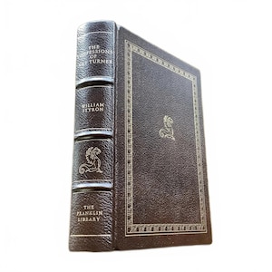 May include: A hardcover book titled "The Confessions of Nat Turner" by William Styron, published by The Franklin Library. The book has a dark brown leather cover with gold lettering and a decorative border. A gold emblem is on the cover.