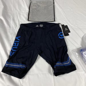 Puede incluir: Pantalones cortos de compresión azul marino oscuro con rayas de chevron azules y blancas en el dobladillo. La palabra "VIRUS" está impresa en azul en la pierna izquierda. Un logotipo azul está en la pierna derecha. Incluye una bolsa transparente con el logotipo "VIRUS".