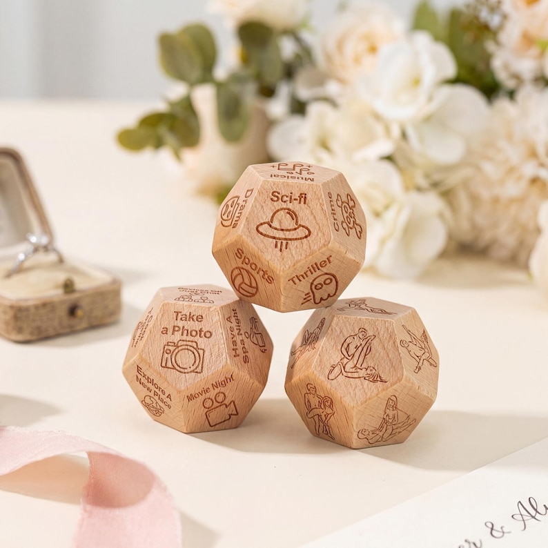 May include: Three wooden dice with engraved icons and text, including a camera, a film reel, and a volleyball. The dice are light brown and appear to be for a game or activity, with themes like "Movie Night" and "Sci-fi".
