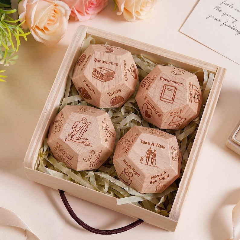 May include: A wooden box holds four wooden polyhedral dice. Each die features etched images and text, with options such as "Sandwiches," "Tacos," "Take a Walk," and "Movie Night." The box is lined with shredded paper.