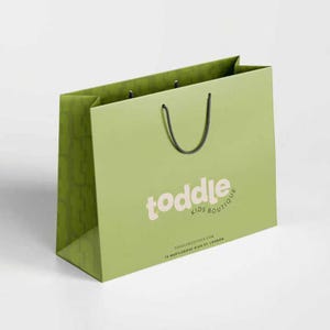 K&ouml;nnte beinhalten: Eine hellgr&uuml;ne Einkaufstasche mit schwarzen Kordelgriffen. Die Tasche zeigt den Text "toddle KIDS BOUTIQUE" in einer weichen, abgerundeten Schriftart. Auf der Unterseite der Tasche befinden sich die Website-Adresse und die Adresse.
