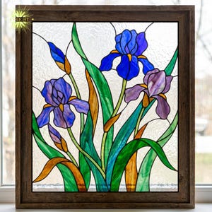 May include: Stained glass panel depicting iris flowers in shades of blue and purple, with green leaves and orange accents. The artwork is set within a dark brown wooden frame, suitable for home decoration.