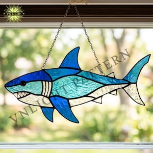 May include: Stained glass shark suncatcher in shades of blue, turquoise, and white, hanging from a chain. The shark features detailed fins, teeth, and eye, with the text "VN-LIGHT" visible in the corner. A decorative ocean-themed item.