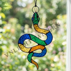 Puede incluir: Un atrapasoles de serpiente de vidrieras con un lazo negro para colgar. La serpiente está segmentada con vidrio azul, verde, amarillo y naranja. El texto "VN-LIGHT PATTERN" es visible.