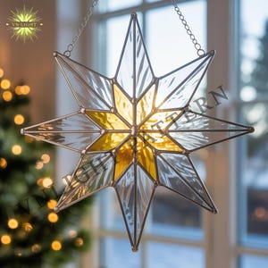 Peut inclure: Étoile décorative en vitrail suspendue par une chaîne. L'étoile présente un schéma de couleurs clair et jaune, avec un motif en étoile au centre. Fabriquée en verre avec un cadre métallique. Le logo "VN-LIGHT" est visible en haut à gauche.