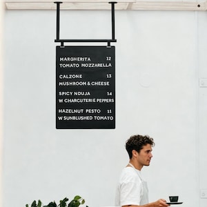 May include: A white ceramic mug with a black handle and the text "But First, Coffee" in a bold, black font. The mug is sitting on a wooden surface. The mug appears to be 12 ounces.