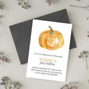 May include: A white invitation card with a watercolor pumpkin illustration. The card includes text that reads "BOBBIE'S first birthday" and event details. A dark gray envelope is behind the card, with floral accents.