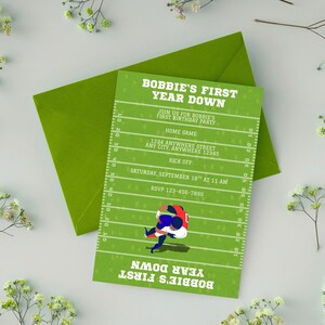 Può includere: Un biglietto d'invito verde con un design da campo di football, con il testo "BOBBIE'S FIRST YEAR DOWN". Il biglietto include i dettagli per una festa di compleanno, come la data, l'ora e le informazioni RSVP. C'è una busta dietro il biglietto.