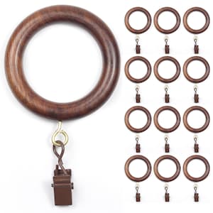 Puede incluir: Juego de anillas de cortina de madera marrón oscuro. Las anillas tienen un acabado liso y pulido, y vienen con clips a juego para colgar cortinas. La imagen muestra una anilla grande con un clip y varias anillas más pequeñas con clips.