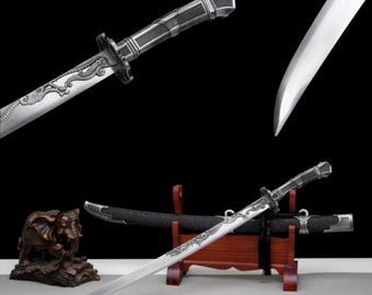 May include: A silver and black sword with a dragon design etched on the blade. The sword is displayed on a wooden stand with a black scabbard. The handle has a textured grip.