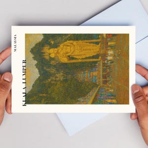 May include: A postcard featuring a golden statue in Kuala Lumpur, Malaysia, set against a backdrop of green hills and a blue sky. The text "KUALA LUMPUR" is printed vertically on the left side. A light blue envelope is behind the postcard.