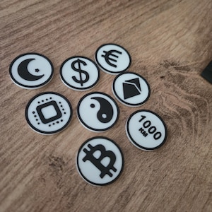 May include: A collection of white and black circular tokens featuring various symbols, including a crescent moon, dollar sign, euro symbol, and Bitcoin logo. One token displays "1000 KM".