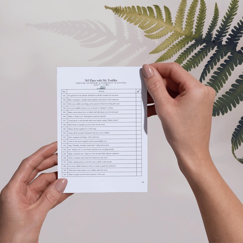 May include: A white paper activity list titled 365 Days with My Toddler, Indoor, Outdoor, & Everyday Activities (Age 1-3 Yrs). The document features a table with numbered days, activity descriptions, and a checkbox column for tracking progress.