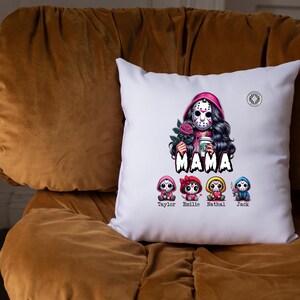 May include: White square pillow with a graphic of a woman in a hockey mask holding a rose and a coffee cup, with the word "MAMA" below. Four cartoon figures are below the word "MAMA", each with a name: Taylor, Emilie, Nathal, and Jack.