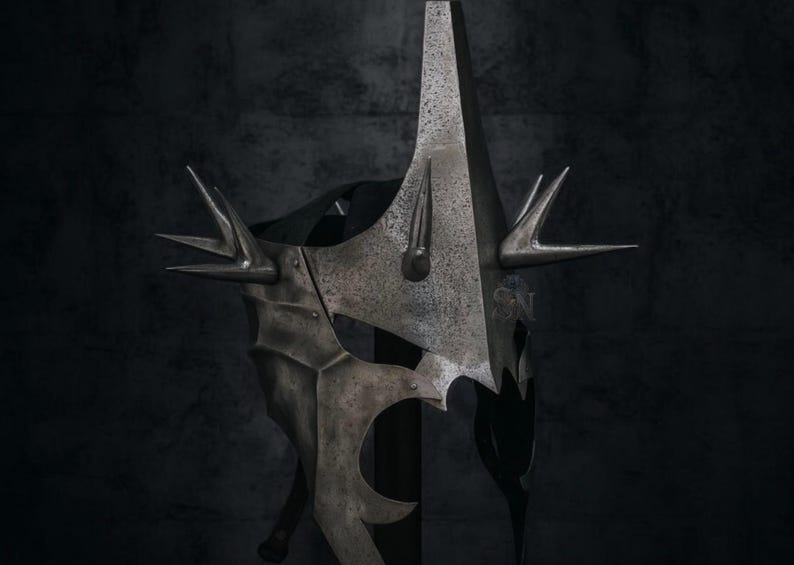 May include: A detailed, metallic helmet with a tall, pointed central spike and multiple smaller spikes. The helmet has a textured, aged appearance, with intricate details and a dark, shadowy background.