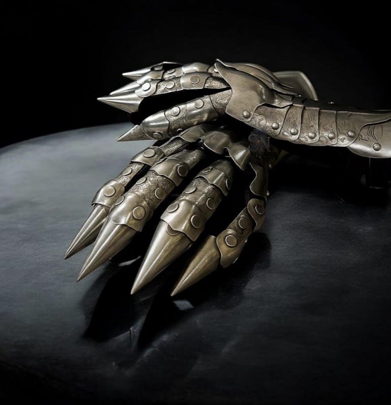 May include: A detailed, metallic claw gauntlet with articulated segments and sharp, pointed talons. The silver-toned armor features intricate detailing and a dark background, creating a dramatic effect. This fantasy-themed accessory is designed for cosplay or display.