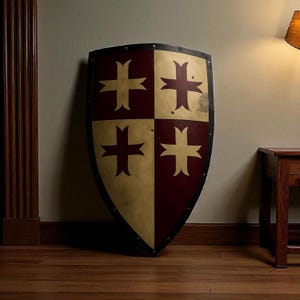 May include: A large, medieval-style shield with a black border and a divided face. The shield is split into four quadrants, alternating between a gold-tan and a deep burgundy color. Each quadrant features a red cross design.
