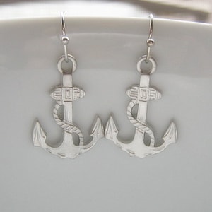 May include: Silver anchor earrings with a rope design. The anchors are detailed with a small square pattern.