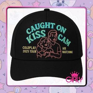May include: Black baseball cap with the text "CAUGHT ON KISS CAM" in turquoise, along with an illustration of a couple. The text "COLDPLAY 2025 TOUR" and "HR WATCHING" are also present. The cap has a curved brim.