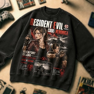 May include: A black crewneck sweatshirt featuring a graphic print of Resident Evil Code: Veronica. The design includes illustrations of Claire Redfield and Leon Kennedy with firearms, the Umbrella Corporation logo, and text details about Rockfort Island.
