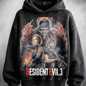 May include: Black hooded sweatshirt featuring a graphic from Resident Evil 3. The design includes three characters and a monster, with the text "RESIDENT EVIL 3" in red and white. The sweatshirt has a distressed, vintage look.