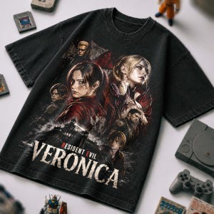 May include: A black short-sleeve t-shirt featuring a graphic print of multiple characters from the Resident Evil series. The text "RESIDENT EVIL VERONICA" is printed in large white letters at the bottom, with red accents on the word "EVIL".