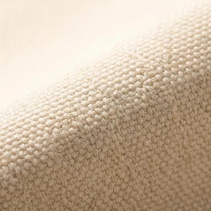 Puede incluir: Primer plano de una tela beige tejida con una superficie texturizada. La tela parece estar tejida apretadamente, con un patr&oacute;n visible de hilos que se cruzan. El color es un tono c&aacute;lido y neutro.