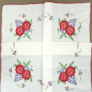 May include: White linen handkerchief with embroidered red peaches and purple grapes. The fruit is surrounded by green leaves and small colorful flowers. The edges are trimmed with a red crocheted border.