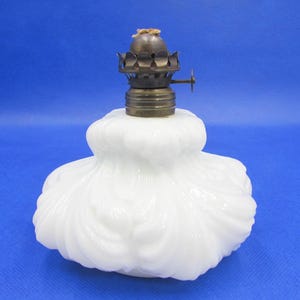 May include: White milk glass oil lamp with a brass burner and a fluted design.