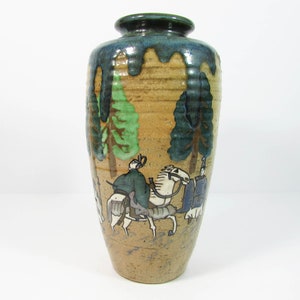 May include: A brown ceramic vase with a blue and green glaze. The vase is decorated with a scene of people riding horses through a forest.