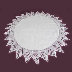 May include: White crocheted tablecloth with a scalloped edge. The tablecloth is round and has a delicate lace pattern.