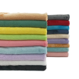 K&ouml;nnte beinhalten: Gestapelte, farbenfrohe Pl&uuml;schstoffe in verschiedenen Farbt&ouml;nen, darunter Beige, Gr&uuml;n, Gelb, Rosa, Blau, Lila, Wei&szlig; und Schwarz. Das weiche, strukturierte Material ist ordentlich gefaltet und zeigt eine Reihe von Farbt&ouml;nen. Das Bild ist gut beleuchtet und hebt die Pl&uuml;schstruktur hervor.