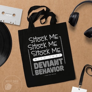 May include: Black tote bag with white text that reads "Shock Me Shock Me Shock Me With That Deviant Behavior" and a copyright symbol with "Sour Pea Design".
