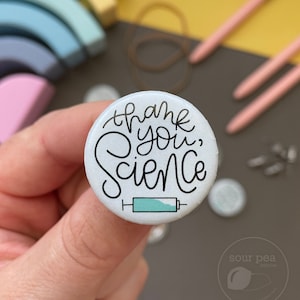 May include: White button with black text that says "Thank you, Science" and a small blue and white syringe graphic.
