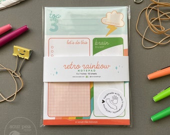 May include: A retro rainbow notepad with a gridded page, a cloud with a lightning bolt, and the text "brain dump" and "let's do this". The notepad is 5x7 inches and has 50 sheets. It is handmade with love in Sacramento, California.