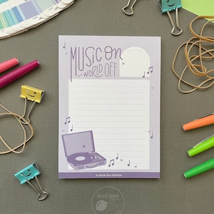 May include: Purple notepad with the text "Music on - World off" and a graphic of a vintage record player. The notepad has a space for writing "Today's Date".
