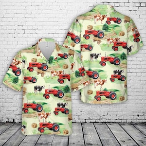 Puede incluir: Camisa de manga corta con un estampado repetido de tractores rojos, vacas y balas de heno sobre un fondo verde claro. La camisa tiene un cuello clásico y un corte relajado.