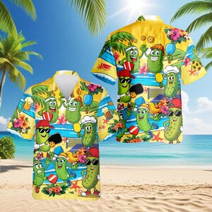 May include: Yellow Hawaiian shirt featuring a playful pickle design. The shirt showcases cartoon pickles engaged in various activities, including pickleball, set against a beach backdrop with palm trees and ocean views. The shirt has a button-down front and short sleeves.
