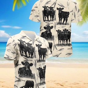Op de afbeelding: Een overhemd met korte mouwen en knopen met een crèmekleurige achtergrond. Het shirt heeft een herhaald patroon van zwarte koe-illustraties en tarwearen. Het shirt wordt gepresenteerd op een strand met palmbomen en de oceaan op de achtergrond.