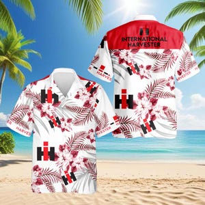 Puede incluir: Camisa hawaiana blanca con cuello rojo y estampado floral. La camisa presenta el logotipo de International Harvester en negro y rojo, junto con el texto "INTERNATIONAL HARVESTER". La camisa tiene mangas cortas y cierre de botones.