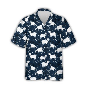 Könnte beinhalten: Marineblaues Kurzarmhemd mit Ziegenmuster. Das Hemd zeigt eine weiße Ziegenillustration, die sich auf dem Stoff wiederholt, zusammen mit kleinen weißen Blumen- und Pflanzendesigns. Das Hemd hat einen klassischen Kragen und eine lockere Passform.