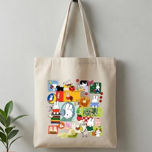 May include: Beige tote bag featuring a collage of colorful cartoon illustrations of rabbits, flowers, and other objects. The bag has two long handles and is made of a sturdy fabric. The illustrations are in a variety of styles and colors.