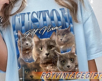 Pode incluir: T-shirt azul claro com um design personalizado com vários retratos de gatos. A palavra "CUSTOM" está arqueada na parte superior, com "Pet Name" abaixo. A camisa também tem o texto "ROYVINTAGEGIFTS" e "CHAMBRAY COMFORT COLORS".