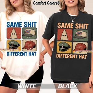 Peut inclure: T-shirts blancs et noirs avec le texte « SAME SHIT DIFFERENT HAT » et des illustrations d'une cagoule, d'un chapeau avec un drapeau confédéré, d'un chapeau militaire et d'un chapeau « Make America Great Again ». Les chemises sont étiquetées « WHITE » et « BLACK ».