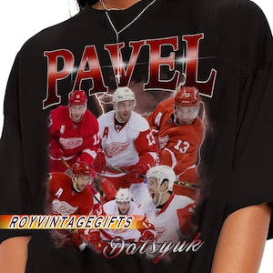 Könnte beinhalten: Schwarzes T-Shirt mit einer Grafik von Eishockeyspielern in rot-weißen Trikots. Das Wort "PAVEL" steht in großen roten Buchstaben oben, mit "Datsyuk" in Kursivschrift unten. Der Text "ROYVINTAGEGIFTS" ist ebenfalls vorhanden.