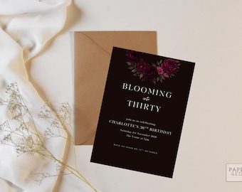 Könnte beinhalten: Eine schwarze Geburtstagseinladung mit floralen Akzenten und dem Text "Blooming into Thirty". Die Einladung enthält Details für eine 30. Geburtstagsfeier, mit einem braunen Umschlag im Hintergrund.