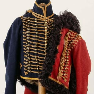 Puede incluir: Una chaqueta militar histórica en azul marino y rojo. La chaqueta azul marino presenta botones y ribetes dorados, con cuello alto. La chaqueta roja tiene ribete de piel negra y detalles dorados. La prenda es probablemente de época.