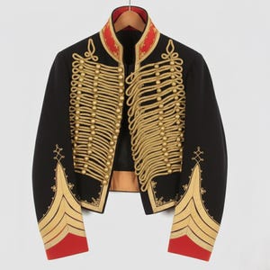 Op de afbeelding: Zwarte jas in militaire stijl met gouden borduursels en accenten. De jas heeft een hoge kraag met rode bies, gouden touwdetails en gouden knoopsluitingen. De mouwen hebben gouden chevronstrepen en rode manchetten.
