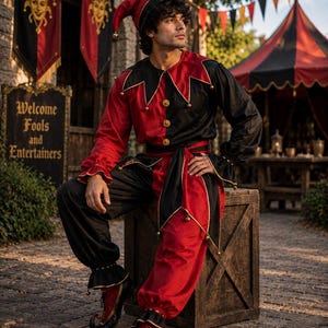 May include: A jester costume featuring a long-sleeved tunic and trousers in a split red and black color scheme. The tunic has a pointed collar with gold bells, gold buttons, and a matching waist sash. A pointed jester hat and curled shoes complete the set.